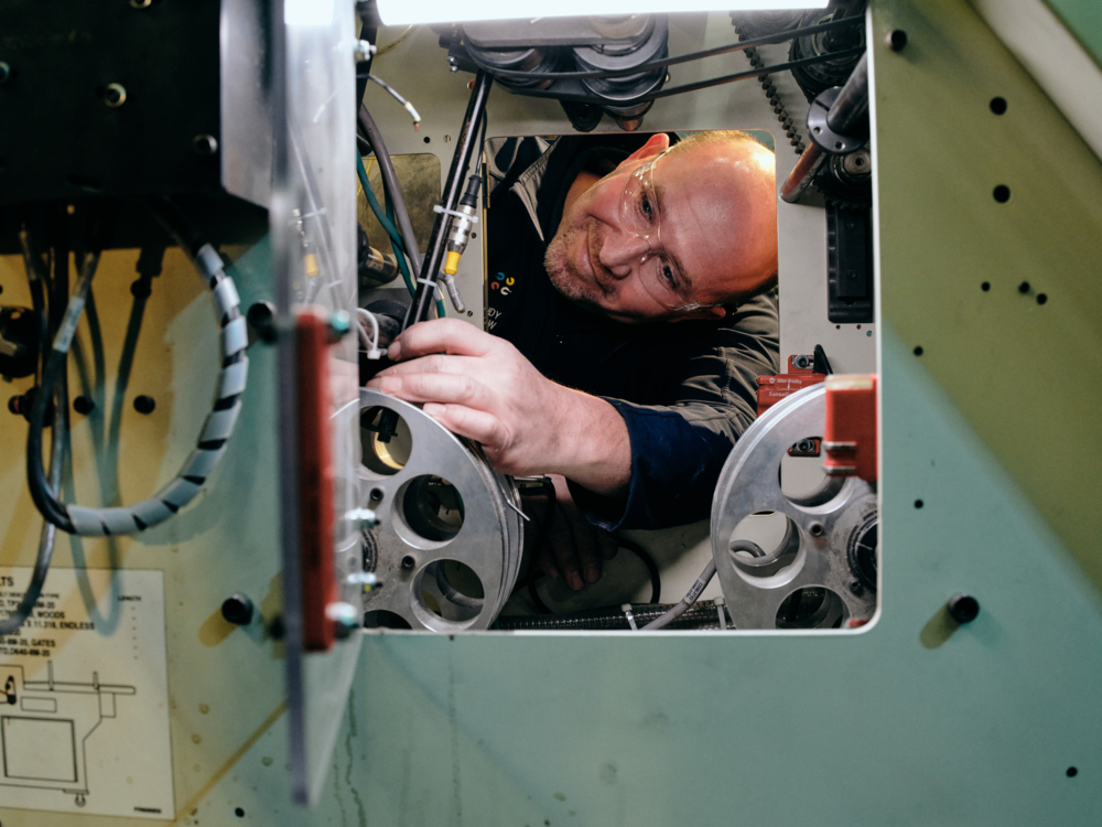 A happy QuadMetalworks employee troubleshooting a piece of equipment