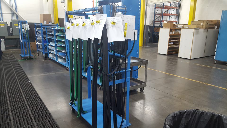 Manufacturing belts produced by QuadMetalworks hanging on a cart by work order