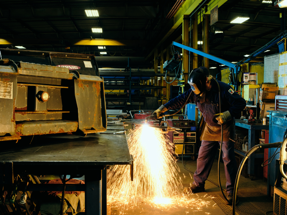 A QuadMetalworks employee using an angle grinder to buff off metal burs